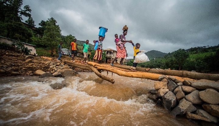 Affected families carry emergency-supplies over a makeshift-bridge-after-the mudslide in Freetown Sierra Leone