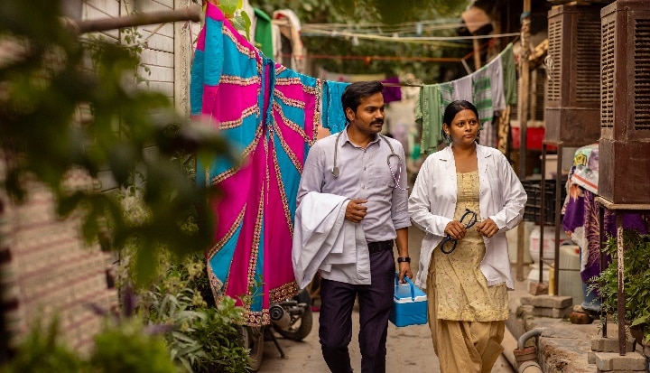 Two doctors walking side-by-side in a village.