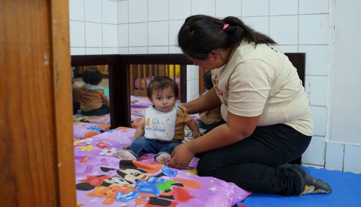 The Business of Care - Women kneeling on the floor with a small child