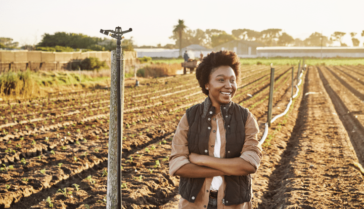 determined African woman standing in a field of crops determined to yield a harvest of crop